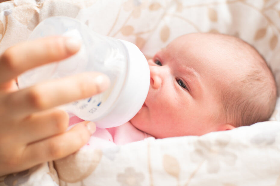 Bebé recién nacido tomando un biberón de leche de fórmula