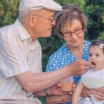 Abuelos dando un potito de frutas a su nieta