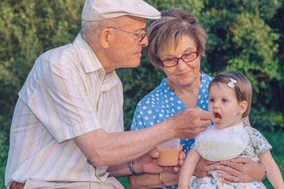 Abuelos dando un potito de frutas a su nieta