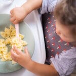 Bebé comiendo lazos de pasta con cuchara