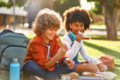 Niños merendando un sandwich en el parque