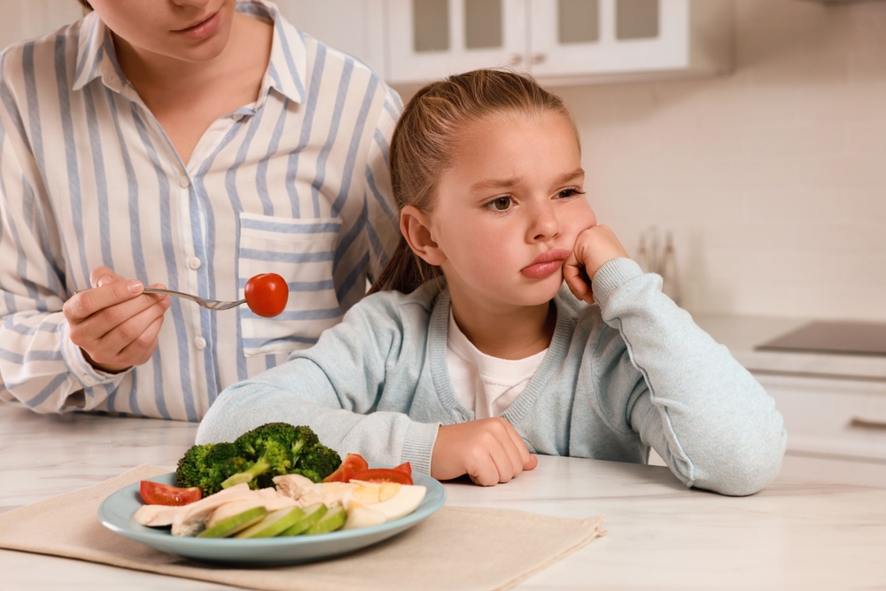 Madre intenta ofrecer verduras a niña que las rechaza