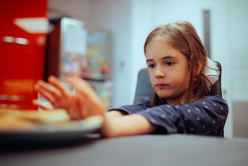 Niña empuja un plato de comida lejos de ella