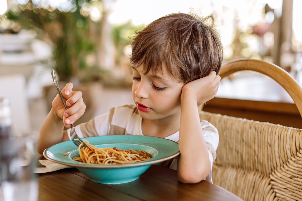 Niño comiendo pasta con tomate