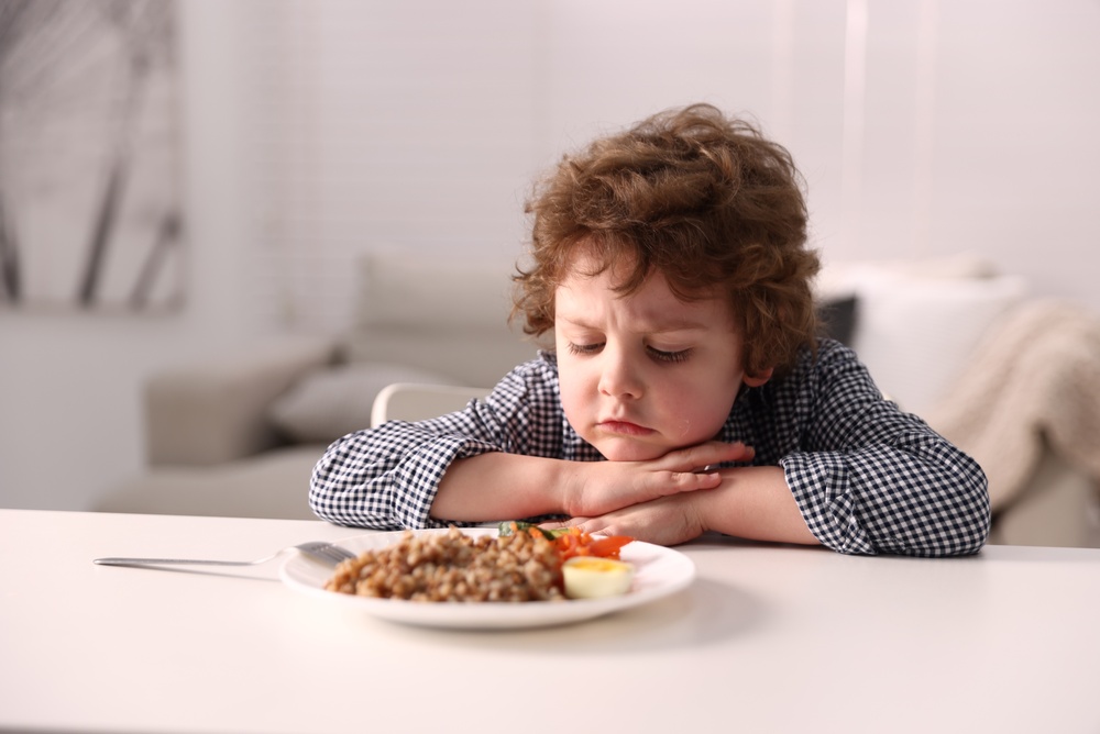 Niño mira un plato de comida con disgusto