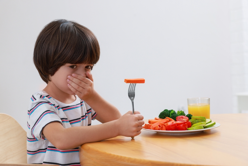 Niño se tapa la boca ante un plato con verduras