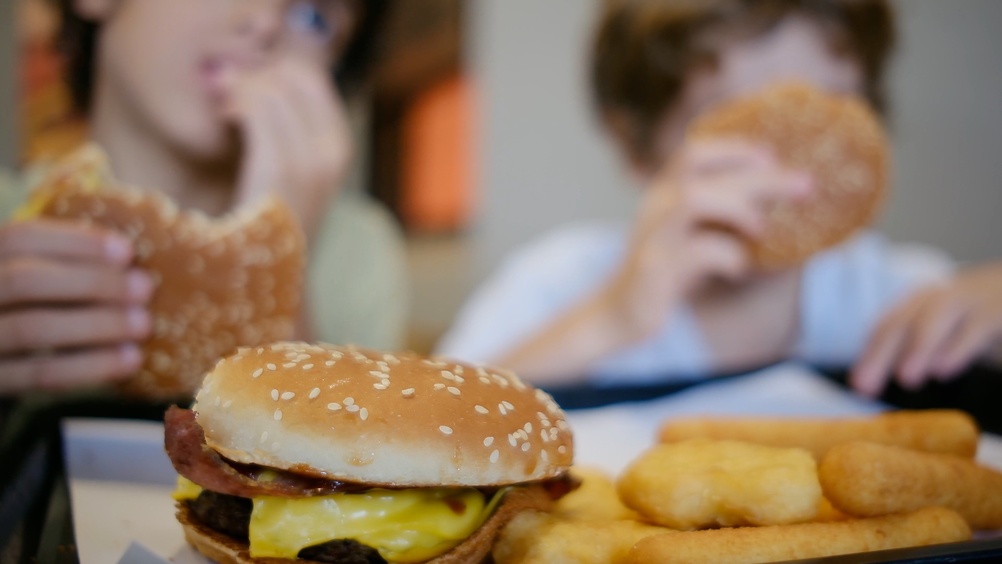 Niños comiendo hamburguesas y rebozados